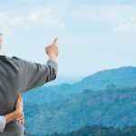 Couple hugging at the top of a mountain looking out on the view