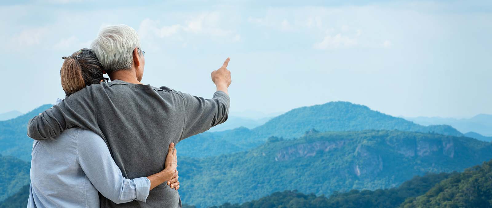 Couple hugging at the top of a mountain looking out on the view